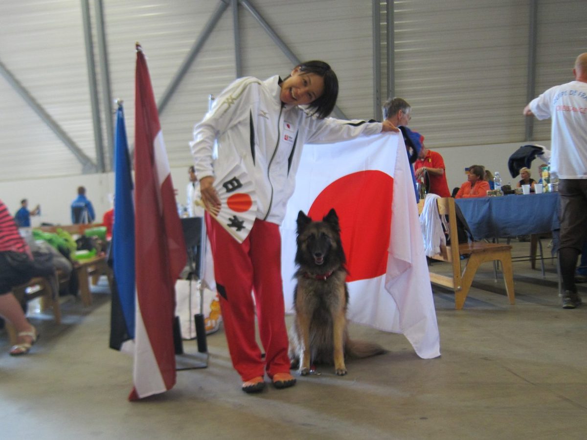 世界大会の会場で日の丸を持つ長和ゆかりと愛犬レッティ